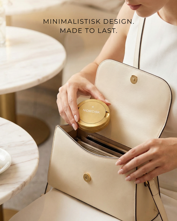 Person holding a beige handbag with a gold snusdosa and nicotine pouch container inside, minimalistic design.